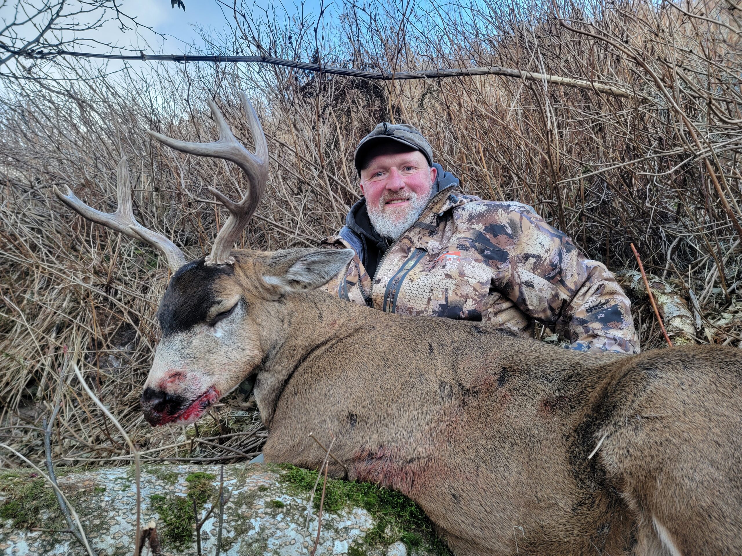 Jim Murphy with blacktail buck in tall grass